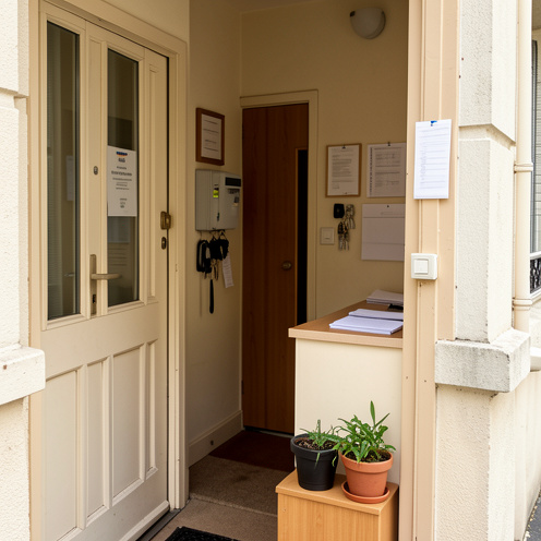 Entrée accueillante d’un immeuble de logements sociaux parisien avec un espace de services, des clés et des documents vierges.